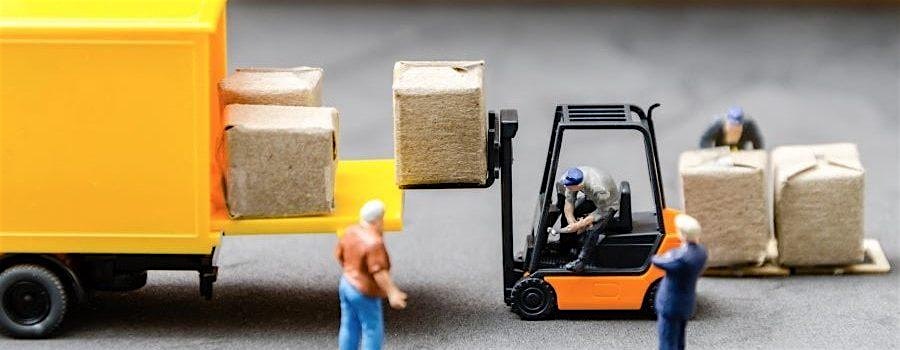 Small-scale forklift loading brown boxes from a yellow delivery truck with workers nearby guiding the process.