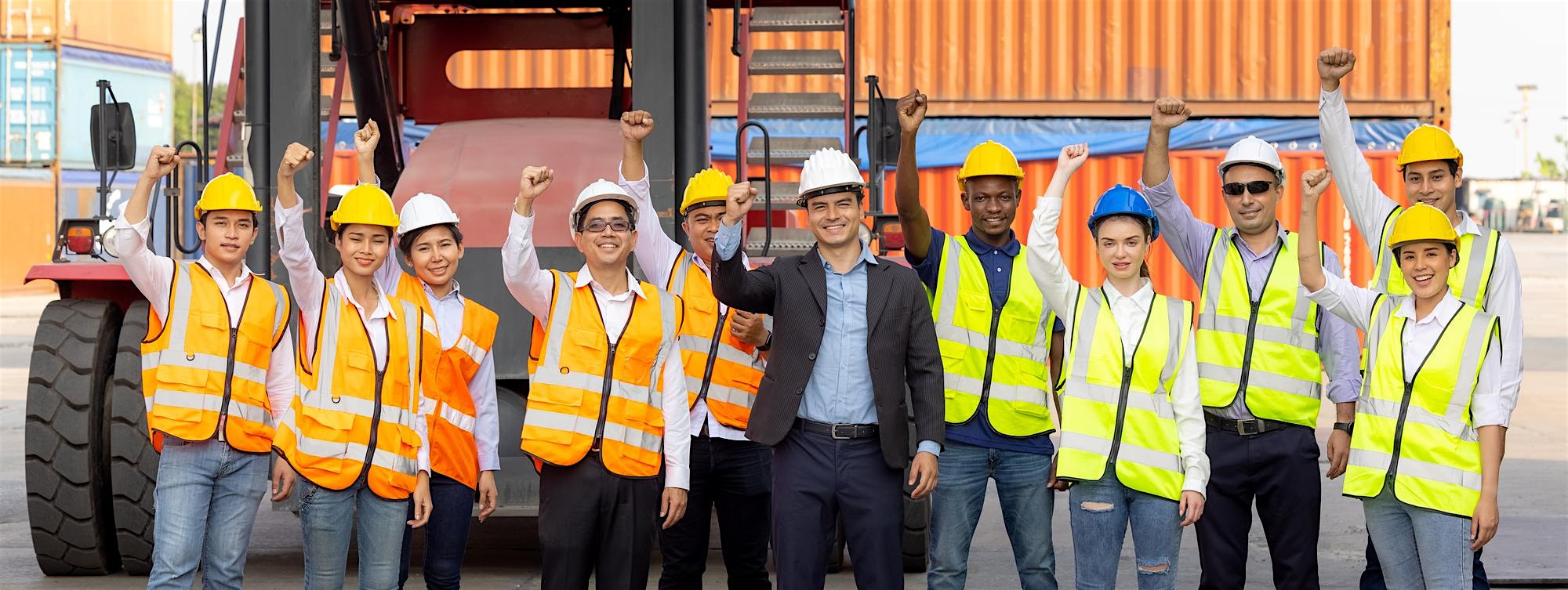 Diverse construction workers in safety vests and hard hats raise fists in unity beside a large forklift at a shipping yard.