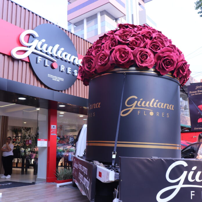 Pink bouquet sculpture of many roses towering over a storefront display, with 'Giuliana Flowers' signage visible nearby outside the shop.